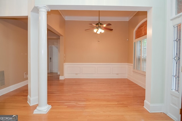unfurnished room with crown molding, decorative columns, and light wood finished floors