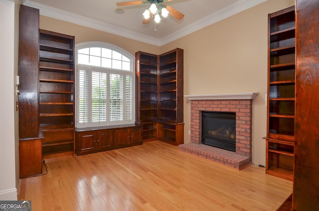 unfurnished living room with light wood-style floors, ornamental molding, ceiling fan, and a fireplace