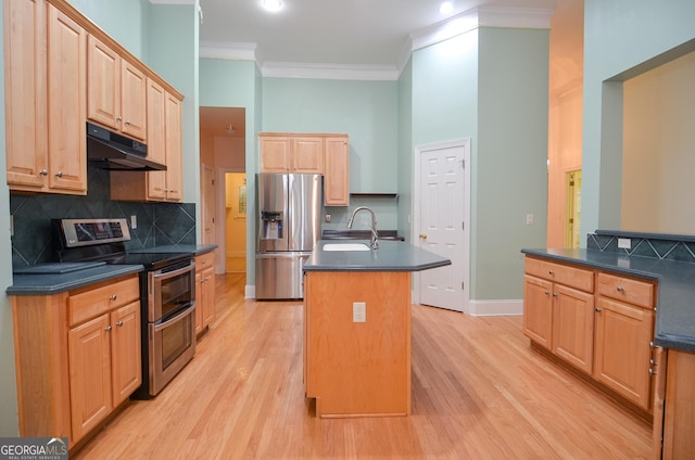 kitchen featuring under cabinet range hood, stainless steel appliances, dark countertops, and a center island with sink