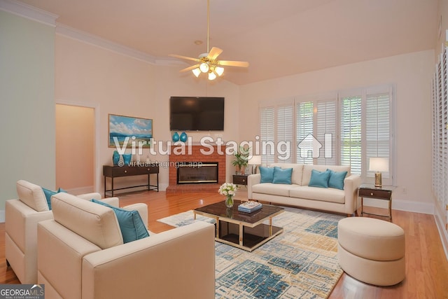 living room featuring ceiling fan, a brick fireplace, wood finished floors, baseboards, and ornamental molding