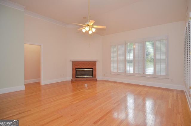 unfurnished living room with crown molding, a brick fireplace, baseboards, ceiling fan, and light wood-type flooring