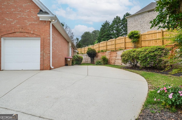 exterior space featuring fence, concrete driveway, and a garage