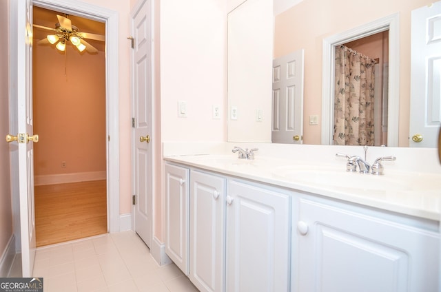 bathroom with double vanity, ceiling fan, tile patterned flooring, a sink, and baseboards