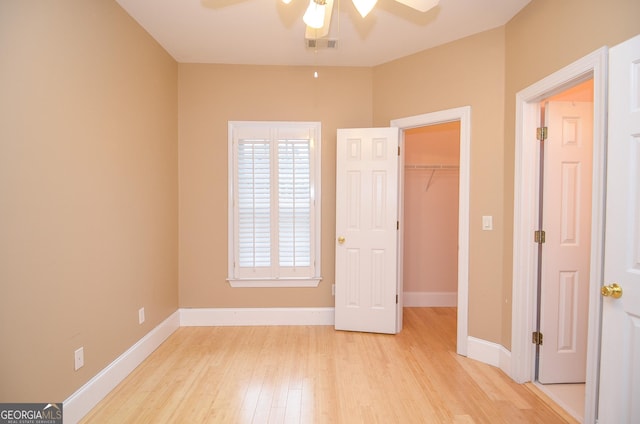 unfurnished bedroom featuring baseboards, visible vents, a walk in closet, and light wood-type flooring