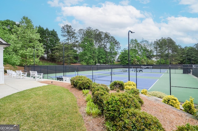 view of tennis court featuring fence and a yard