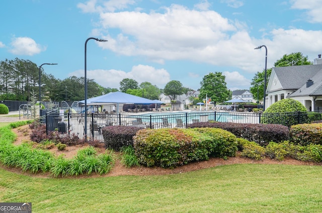 exterior space featuring a lawn, fence, and a pool