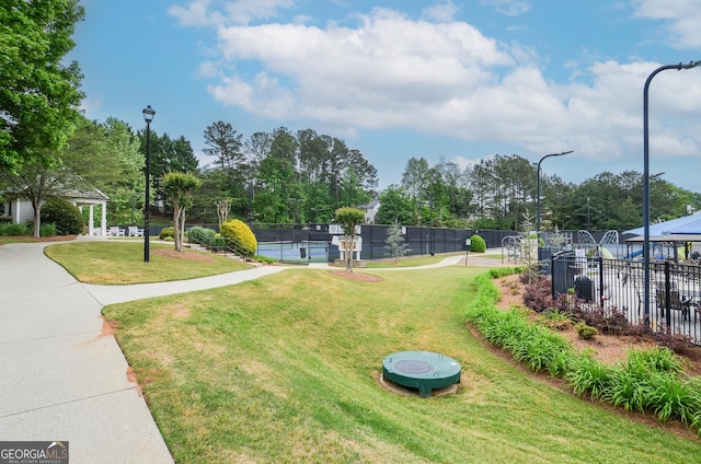 view of community featuring a lawn, fence, and a gazebo