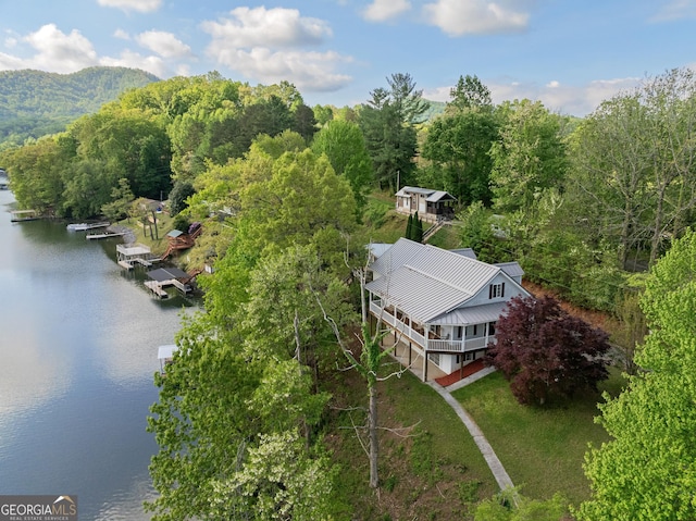 birds eye view of property with a water view and a wooded view