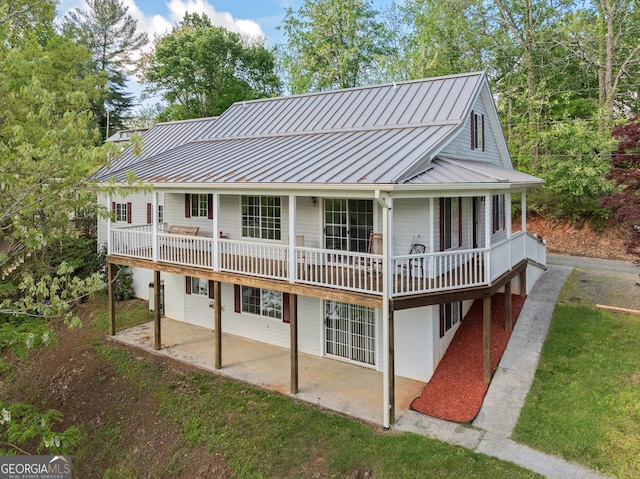 back of property with a standing seam roof, a lawn, a patio area, and metal roof