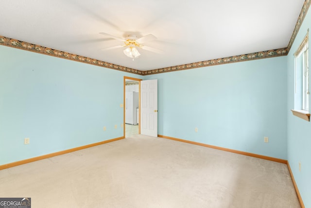 carpeted empty room featuring baseboards and a ceiling fan