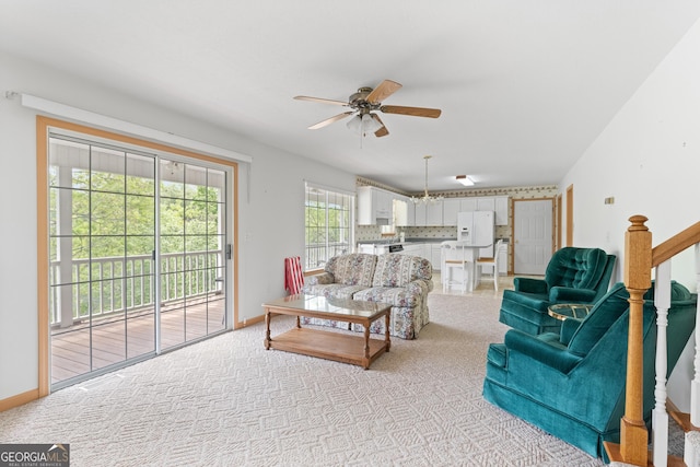 living room with stairway, baseboards, ceiling fan, and light colored carpet