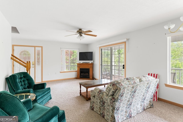 carpeted living area with baseboards, ceiling fan, stairway, and a fireplace