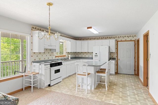 kitchen with a breakfast bar, white appliances, white cabinetry, baseboards, and light floors