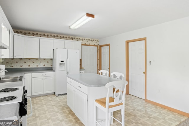 kitchen with light floors, a kitchen bar, white cabinets, a sink, and white fridge with ice dispenser