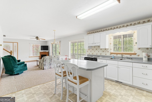 kitchen with range, a sink, white cabinets, light floors, and under cabinet range hood
