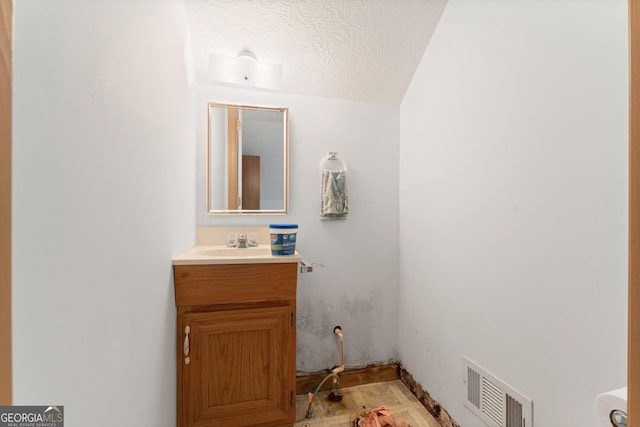 bathroom featuring a textured ceiling, visible vents, and vanity