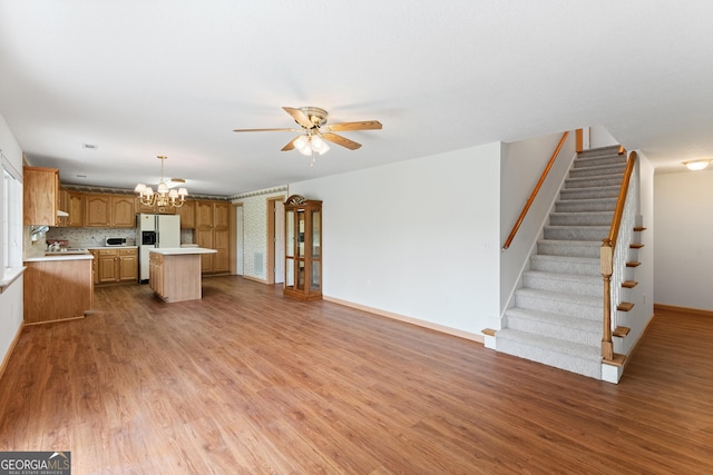 kitchen featuring a center island, light countertops, ceiling fan with notable chandelier, light wood finished floors, and white fridge with ice dispenser