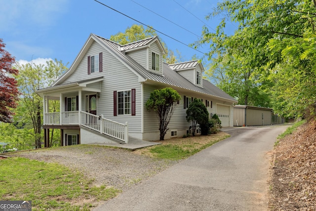 view of front of home featuring a garage, aphalt driveway, covered porch, a standing seam roof, and metal roof