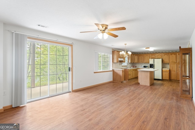 kitchen featuring a kitchen island, visible vents, light countertops, ceiling fan with notable chandelier, and white fridge with ice dispenser