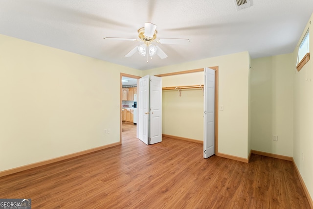 unfurnished bedroom with baseboards, a closet, light wood finished floors, and visible vents
