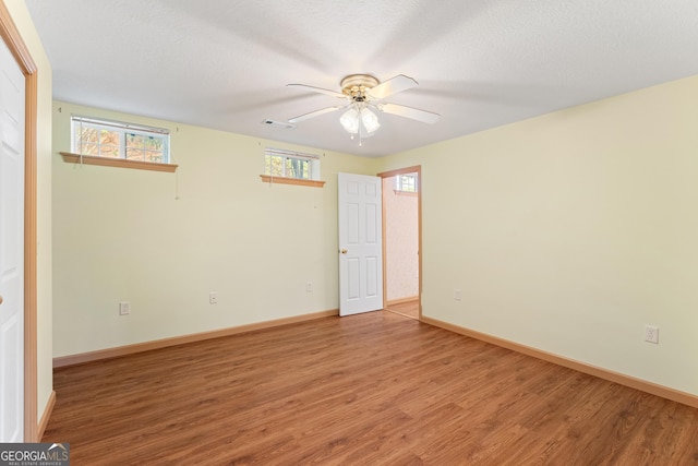 empty room with a healthy amount of sunlight, a ceiling fan, and wood finished floors