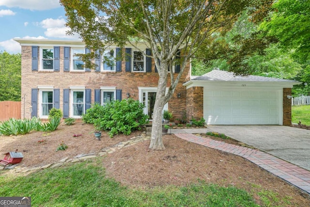 colonial inspired home with brick siding, a garage, fence, and driveway