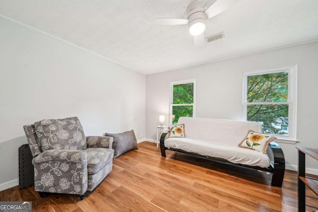 sitting room with a ceiling fan, baseboards, visible vents, and wood finished floors