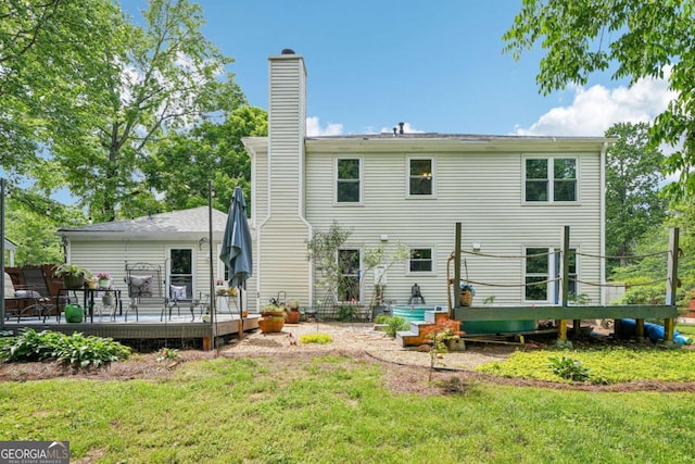 back of house featuring a lawn, a wooden deck, and a chimney