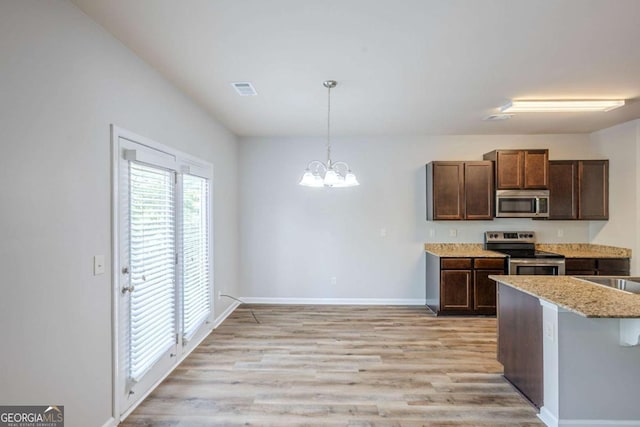 kitchen with hanging light fixtures, baseboards, light wood finished floors, a chandelier, and stainless steel appliances