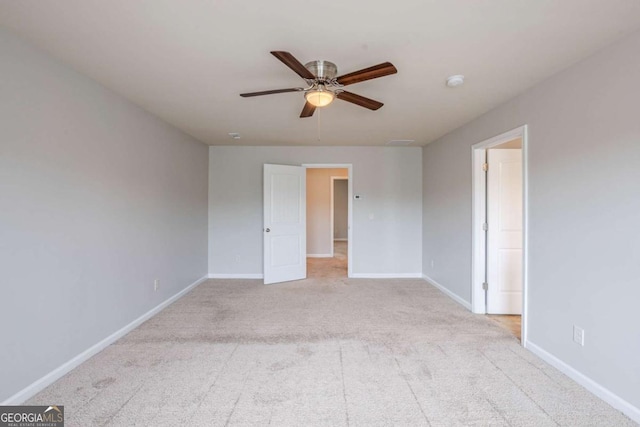 carpeted spare room with a ceiling fan and baseboards