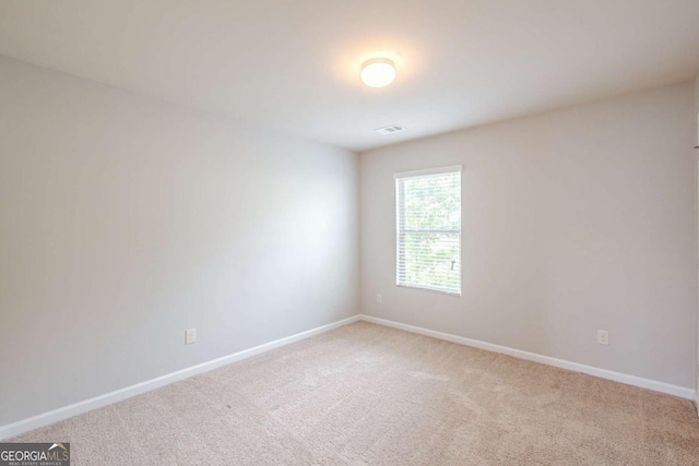 spare room with light colored carpet, baseboards, and visible vents