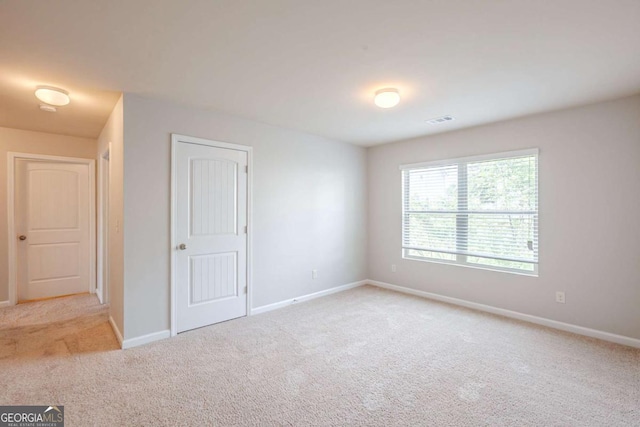 carpeted empty room featuring baseboards and visible vents