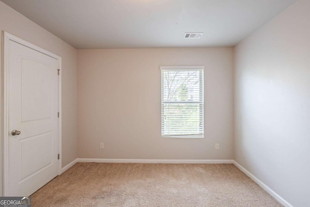 empty room featuring visible vents, baseboards, and light carpet