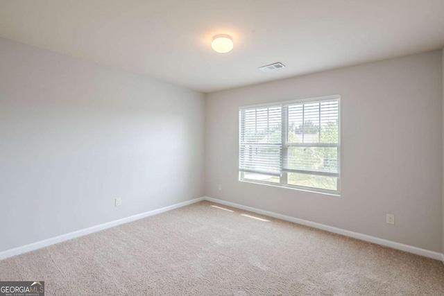 carpeted spare room featuring visible vents and baseboards