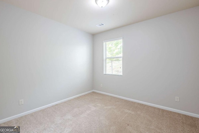 spare room with baseboards, light colored carpet, and visible vents