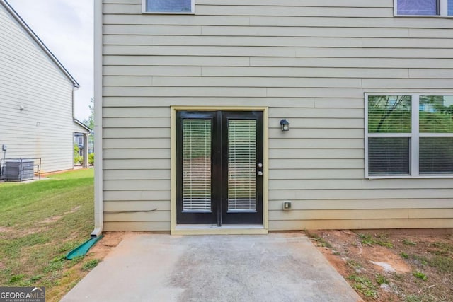 property entrance featuring a lawn, a patio, and central air condition unit
