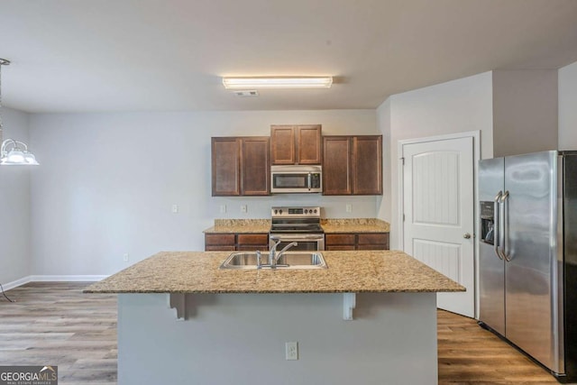 kitchen featuring a sink, light wood-style flooring, a breakfast bar, and stainless steel appliances