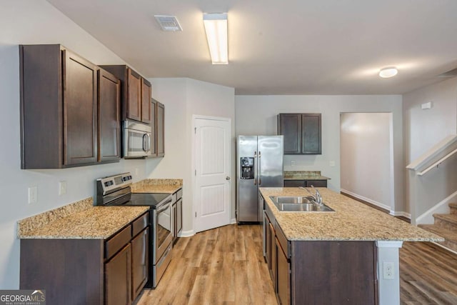 kitchen featuring a sink, appliances with stainless steel finishes, light wood-style floors, and dark brown cabinets