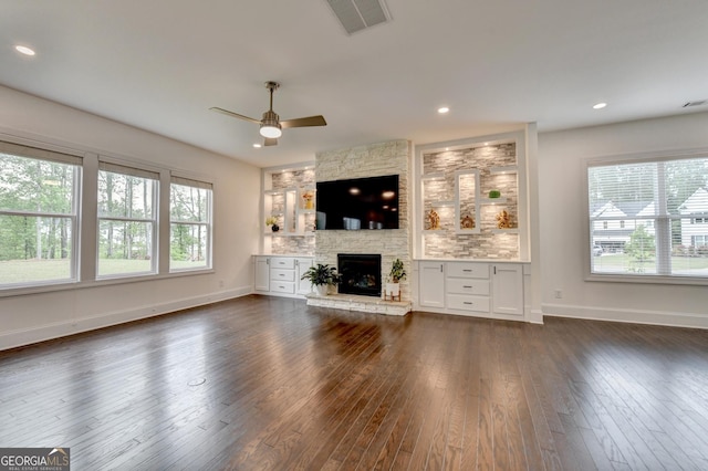 unfurnished living room with visible vents, dark wood-style flooring, a fireplace, baseboards, and ceiling fan