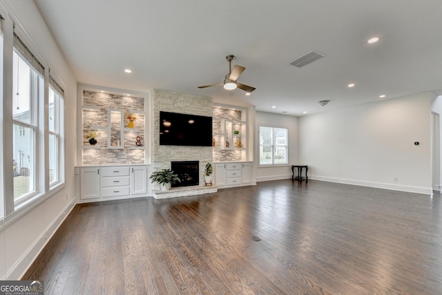 unfurnished living room with visible vents, dark wood-style flooring, a stone fireplace, recessed lighting, and a ceiling fan