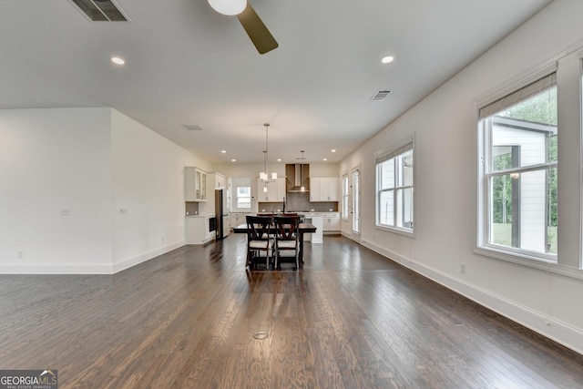 dining area featuring visible vents, dark wood finished floors, ceiling fan with notable chandelier, and baseboards