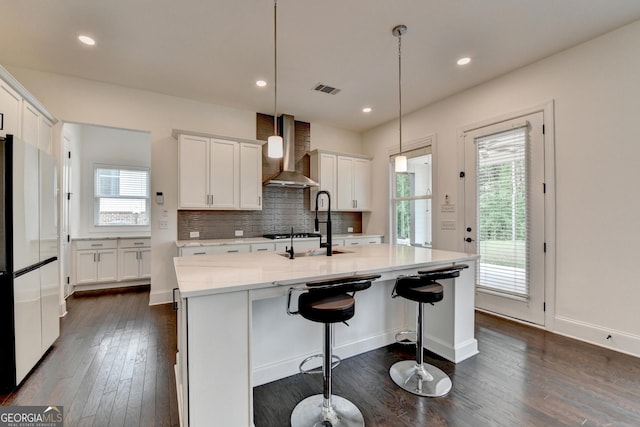 kitchen featuring visible vents, freestanding refrigerator, dark wood-type flooring, wall chimney exhaust hood, and white cabinets