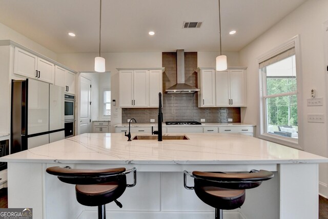 kitchen with wall chimney range hood, a wealth of natural light, backsplash, and visible vents