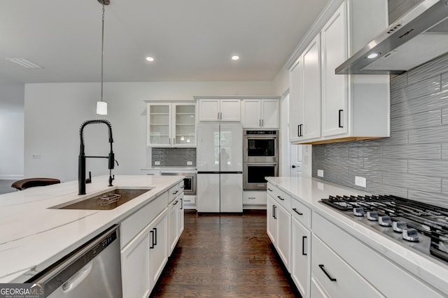 kitchen with appliances with stainless steel finishes, range hood, tasteful backsplash, a sink, and recessed lighting