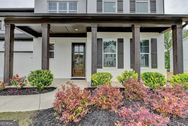 doorway to property featuring brick siding and covered porch