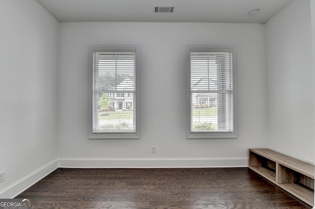 spare room with visible vents, baseboards, and dark wood-style flooring