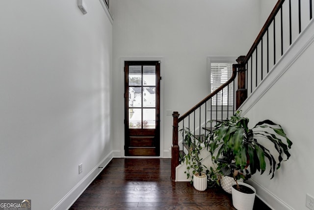 entryway with a healthy amount of sunlight, a high ceiling, stairs, and wood finished floors