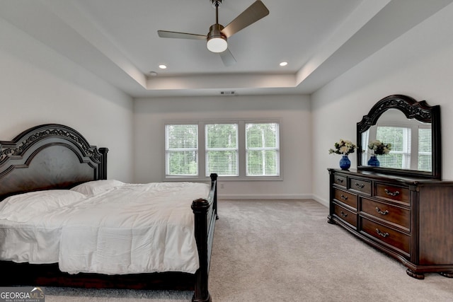 bedroom featuring light carpet, a raised ceiling, recessed lighting, baseboards, and a ceiling fan