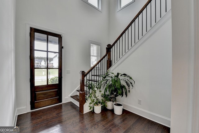 entrance foyer featuring dark wood finished floors, stairs, a towering ceiling, and a wealth of natural light