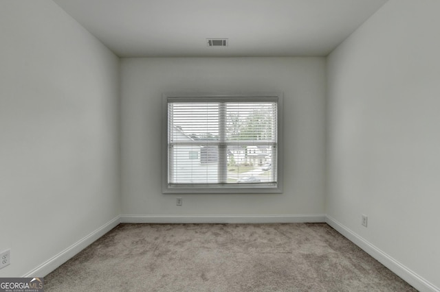 carpeted empty room featuring baseboards and visible vents